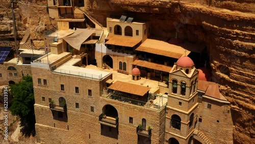 Aerial: Drone Tilt Down Shot Of Famous Monastery On Cliff During Sunny Day - Judaean Desert, Israel photo