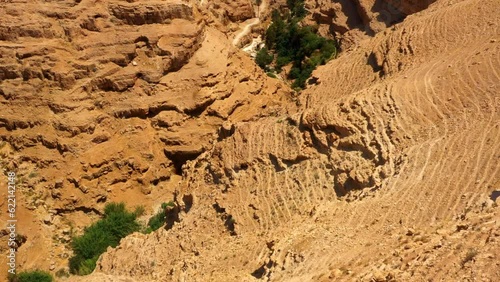 Aerial Tilt Up Shot Of Monastery Of Saint George Of Choziba On Cliff, Drone Flying Forward On Sunny Day - Judaean Desert, Israel photo