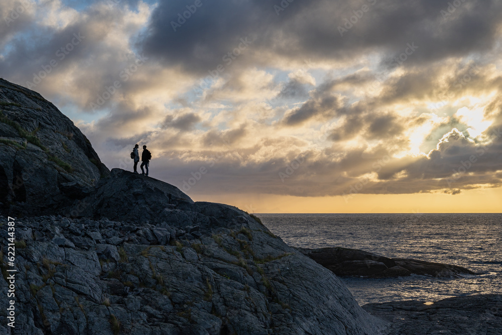silhouette of young couple on the hill in the morning with sunlight above the sea