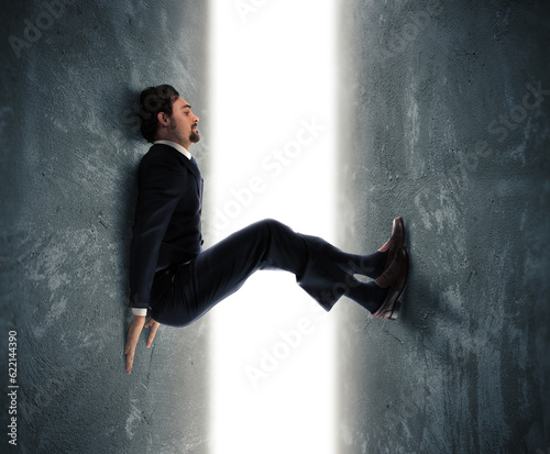 Foto Businessman man trapped between two walls strives to push