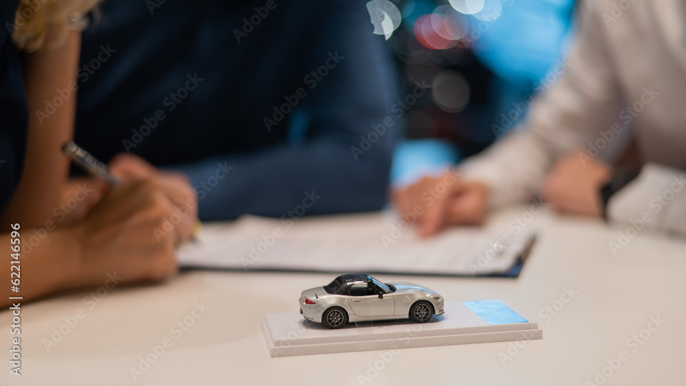 Close-up of the couple's hands signing a contract to buy a car salon.