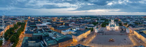 Lit streets and buildings by church and square in European city at dawn