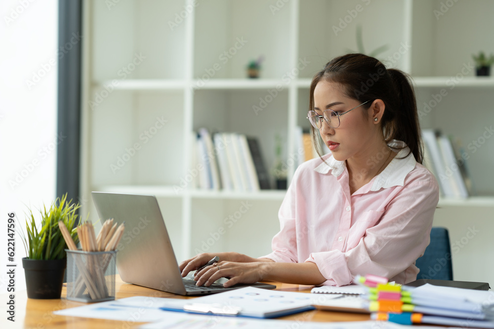 Cropped image of asian businesswoman analyzing paperwork using laptop to actively search for information tense expressions at the office. Cropped image of asian businesswoman analyzing paperwork using laptop to actively search for information tense expressions at the office.