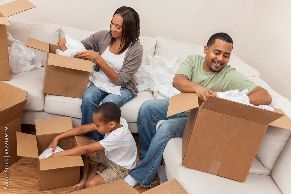 African American family, parents and son, adults and child, unpacking boxes and moving into a new home. African American family, parents and son, adults and child, unpacking boxes and moving into a new home.