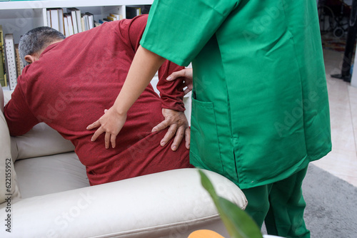 Woman physiotherapist massaging back of elderly man, having chiropractic back adjustment 