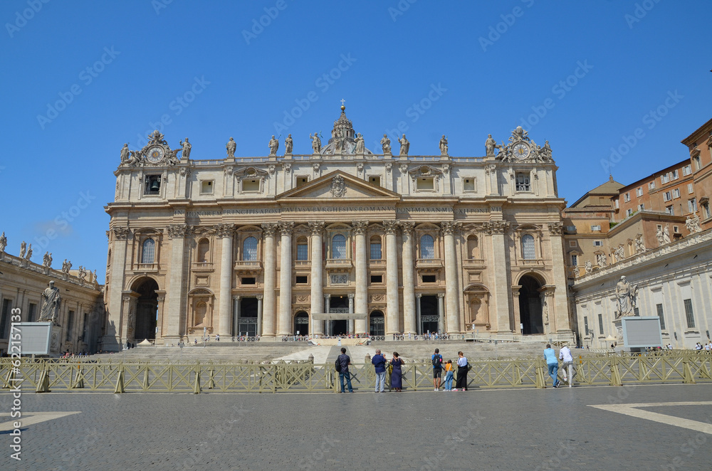 View of Saint Peter's Basilica exterior facade with sculptures, obelisk and dome.