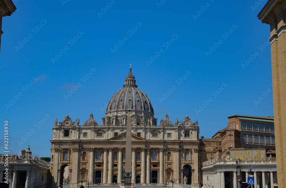 View of Saint Peter's Basilica exterior facade with sculptures, obelisk and dome.