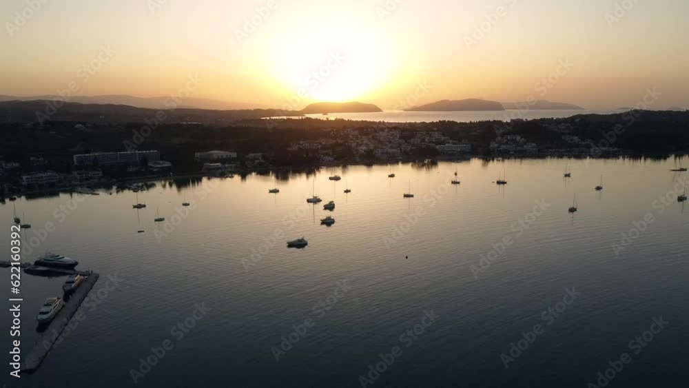 Drone view of coastal mediterranean town with boats anchored with the sunrise in the background Drone view of coastal mediterranean town with boats anchored with the sunrise in the background