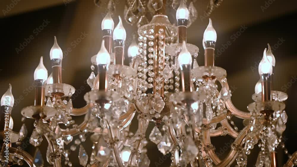 A crystal chandelier with crystals shimmers with bright lights. The ceiling light is brightly reflecting. Volumetric lamp with crystals rotates smoothly.
