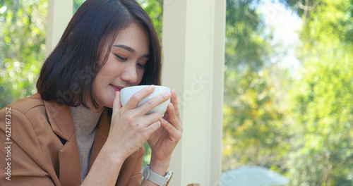 Woman holding coffee cup relaxing after work at office warm taste in cafe. Close up hands of woman sitting office desk holding sweet coffee cup relax and enjoy with happy time. Hot coffee mug in hand