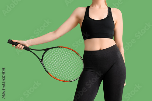 Young woman in sportswear and with tennis racket on green background © Pixel-Shot