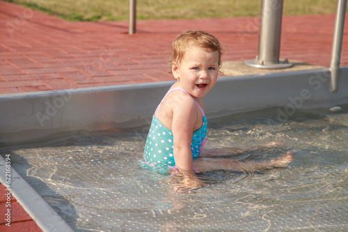 Little cute girl in a blue swimsuit in the pool. Active healthy lifestyle. Children on vacation on vacation. Baby 2 years old plays in the water outdoors. 
