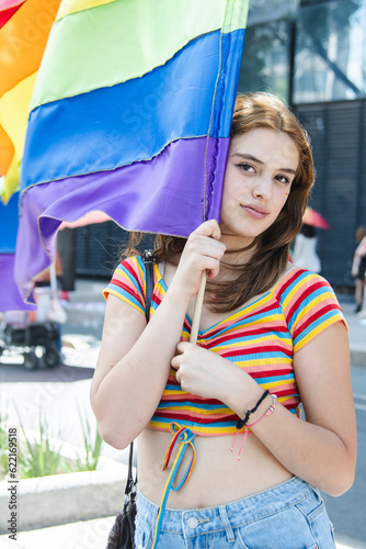 Pretty caucasian woman waving a gay pride flag.