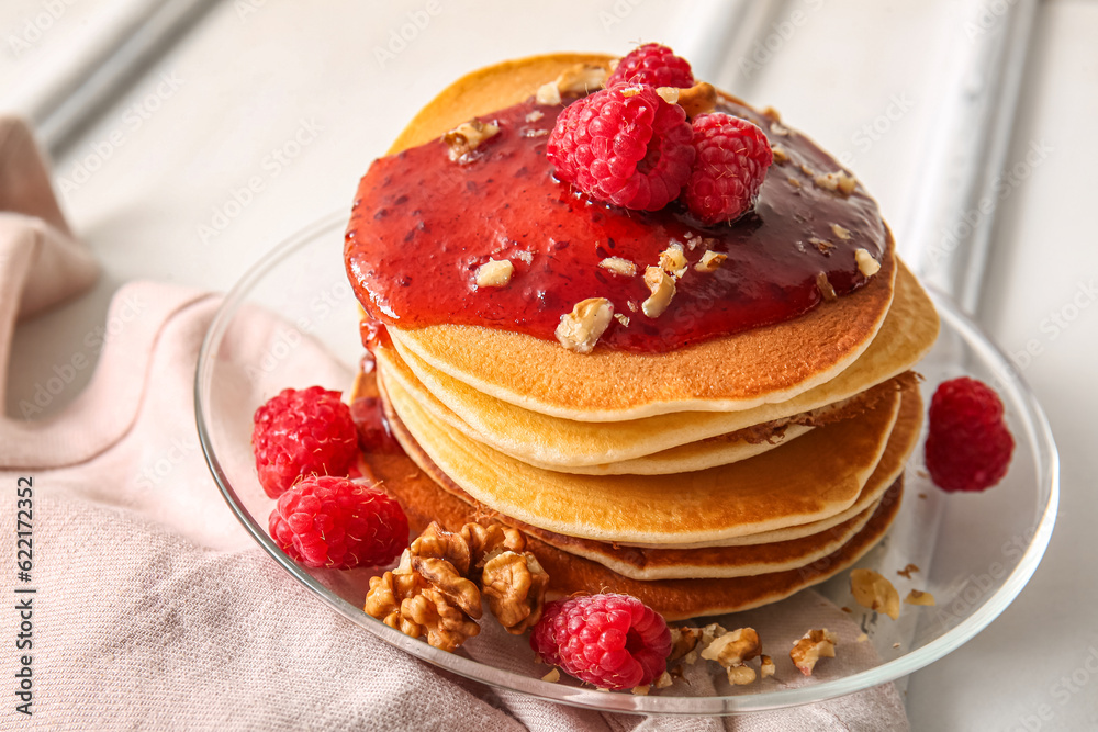 Plate of tasty pancakes with raspberries and nuts on white wooden background Plate of tasty pancakes with raspberries and nuts on white wooden background