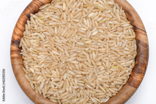 Suchy ryż brązowy o długich ziarnach w miseczce na białym tle