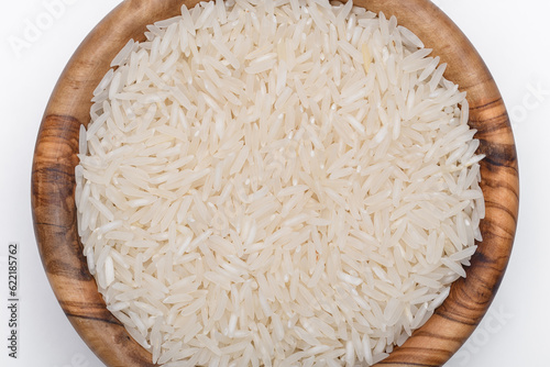 Ziarna ryżu białego ułożone w misce z drewna oliwnego na białym tle