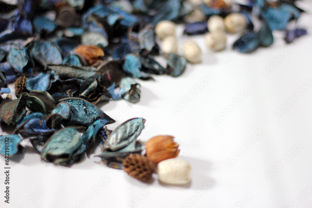 Obraz premium A mix of dry flowers, leaves, petals, and other plant parts. Potpourri background. Purple and blue tone leaves, white color and wood grain background shot.