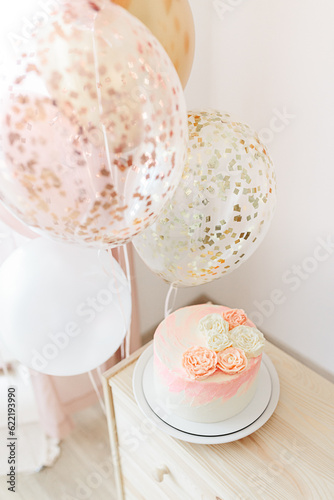 Birthday celebration for child girl at home light pink and gold colors. cake with flowers, balloons
