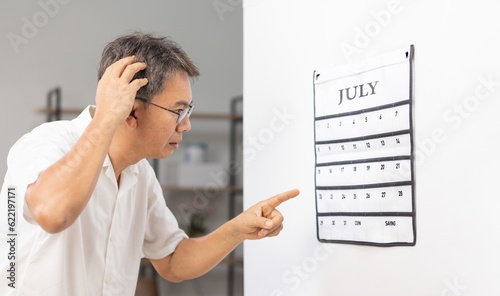 Tableau sur toile Confused Asian Senior Man With Dementia Looking At Wall Calendar