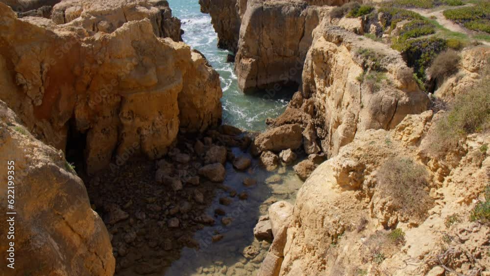 Scenery Of Clay Orange Cliffs At The Rugged Shore Of Praia do Evaristo In Albufeira, Algarve, Portugal. Tilt-up Shot Scenery Of Clay Orange Cliffs At The Rugged Shore Of Praia do Evaristo In Albufeira, Algarve, Portugal. Tilt-up Shot