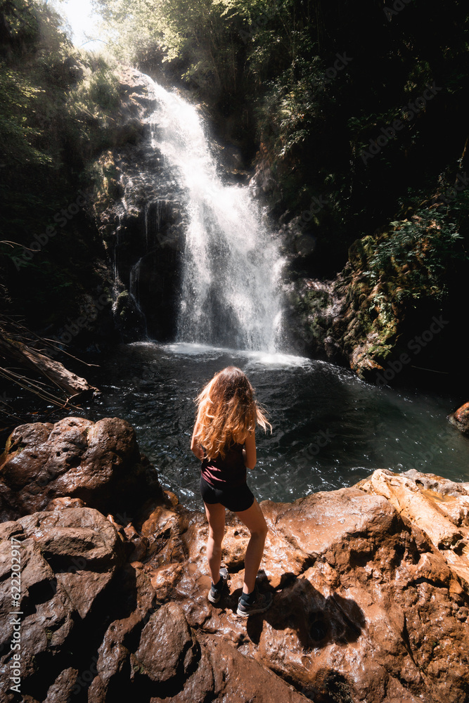 Obraz premium young woman enjoys the views of the Xorroxin waterfall and pool in the Baztan valley in summer