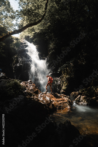 young man with backpack at the beautiful Xorroxin waterfall in the green valley of Baztan in Euskal Herria, Navarra