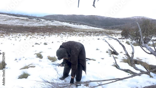 A traditional bushman preparing fire wood out in the snowy mountains. photo