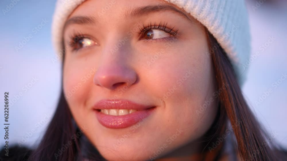 Headshot of young beautiful happy woman in sunrise sunshine looking away smiling. Close-up portrait of relaxed confident Caucasian female tourist enjoying dawn on winter morning outdoors. Slow motion Headshot of young beautiful happy woman in sunrise sunshine looking away smiling. Close-up portrait of relaxed confident Caucasian female tourist enjoying dawn on winter morning outdoors. Slow motion