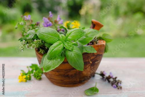 Fresh herbs in a wooden mortar