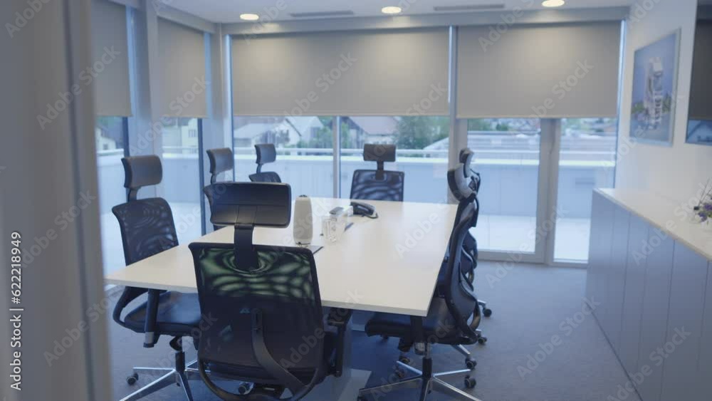 Office meeting room with no people view behind window with white blinds handheld shot. Desk and chairs in modern empty conference boardroom at day time Office meeting room with no people view behind window with white blinds handheld shot. Desk and chairs in modern empty conference boardroom at day time