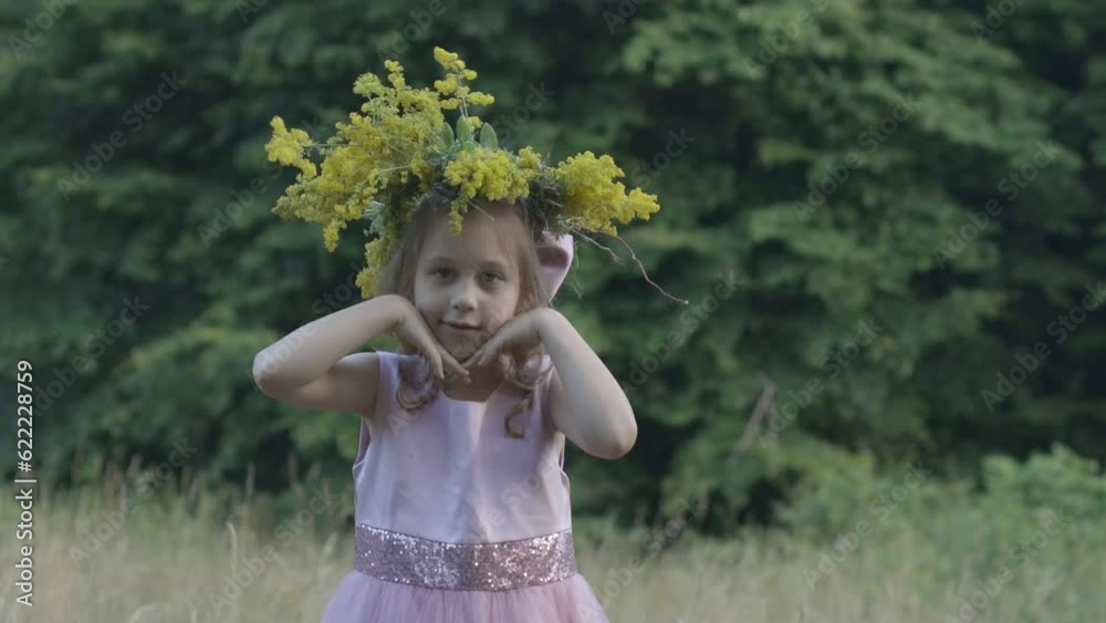 Little girl in a pink dress looking cute with a crown of wild flowers on her head Little girl in a pink dress looking cute with a crown of wild flowers on her head