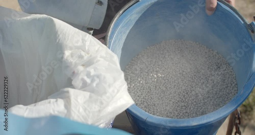 Measure granular soil fertilizer put in a basket and to put the plants.Granular soil fertilizer in white color in a bucket.Farmers bring fertilizer to nourish vegetables.(Close up hand)