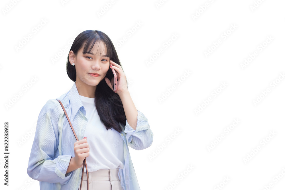 Confident young Asian woman who wears blue white shirt and bag smiles happily while she holds talks to customer on phone with smartphone as she commute to work while isolated on white background. Confident young Asian woman who wears blue white shirt and bag smiles happily while she holds talks to customer on phone with smartphone as she commute to work while isolated on white background.