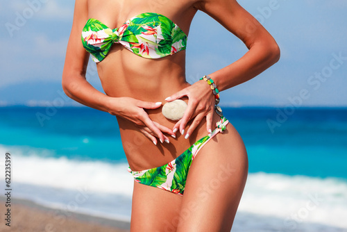 Woman in bikini on the beach. Tanned model sexy body and summer sea