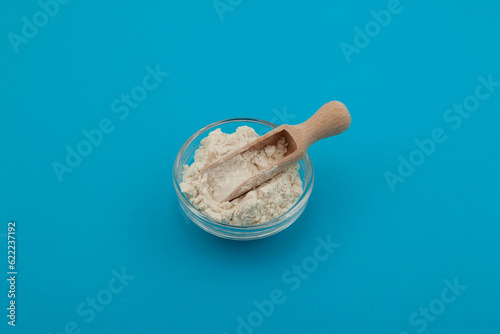 Guar gum powder or guaran in glass bowl with wooden measuring scoop. Food additive E412. Thickening agent. Guar Gum widely used in food industry photo