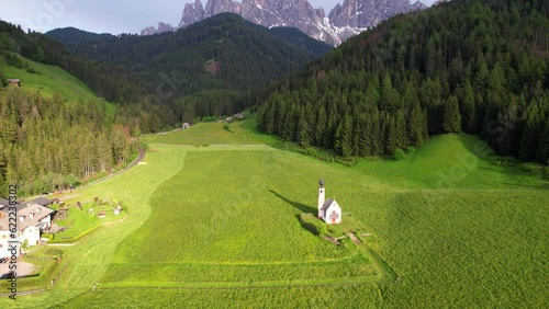 Aerial tilt up of San Giovanni in Ranui Church revealing Odle mountain range, Italy photo