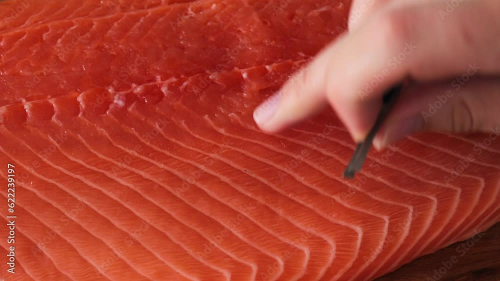 The cook is taken out with tweezers bones from red fish. Raw salmon or trout
The cook is taken out with tweezers bones from red fish. Raw salmon or trout