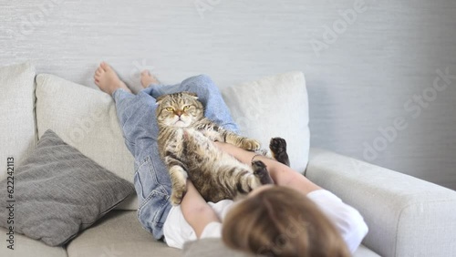 A girl with her tabby cat is resting on the sofa.