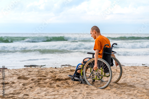 Portrait a disabled person in a wheelchair on the beach pensive by the sea © unai