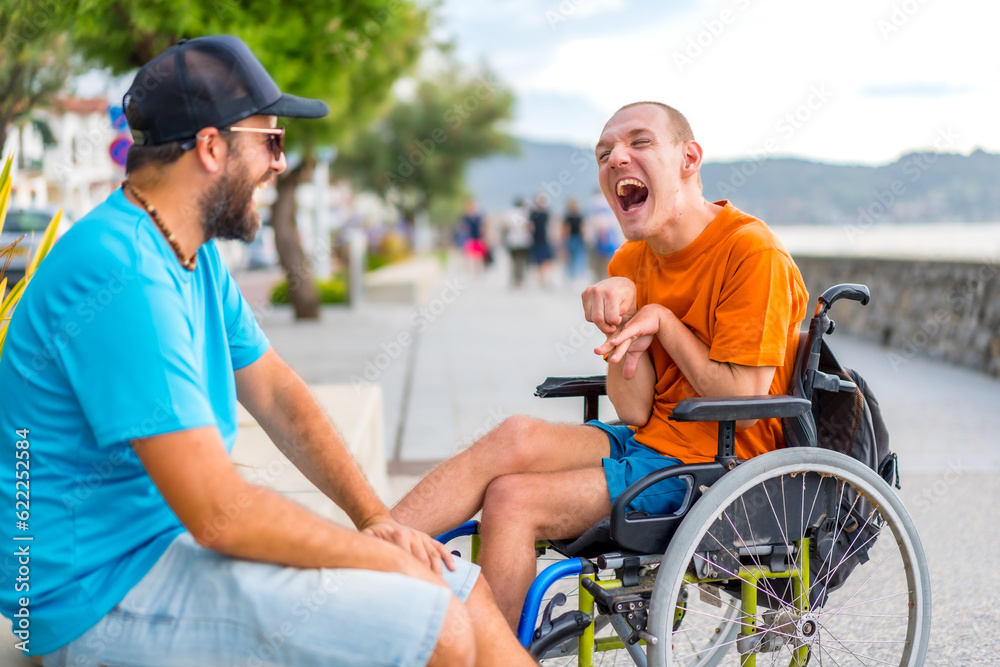 A disabled person in a wheelchair with a friend on summer vacation having fun laughing a lot