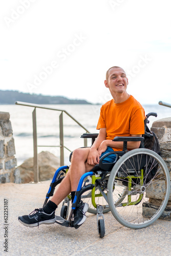 Portrait of pretty cheerful disabled person in wheelchair at the beach on summer vacation smiling