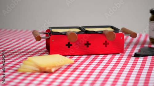 Swiss cheese on red raclette oven, lateral view photo