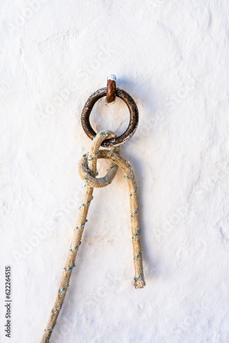 Closeup of a rope hanging from a ring with a beautiful knot. Village of Folegandros Island. Cyclades of Greece. © LabbePhotography