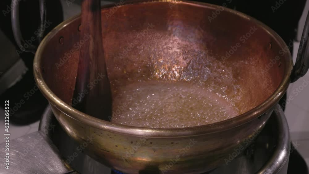 a worker stirs a bowl of sugar and water to make toffee at a confectionery store in cordoba, spain a worker stirs a bowl of sugar and water to make toffee at a confectionery store in cordoba, spain