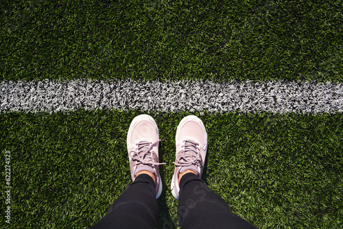 Legs of a personstanding on artificial green grass behind start line photo