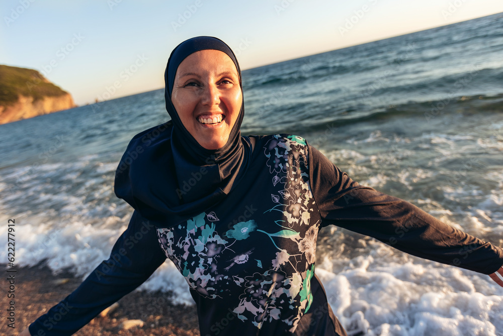 A woman in hijab standing on the beach looking at the horizon A woman in hijab standing on the beach looking at the horizon