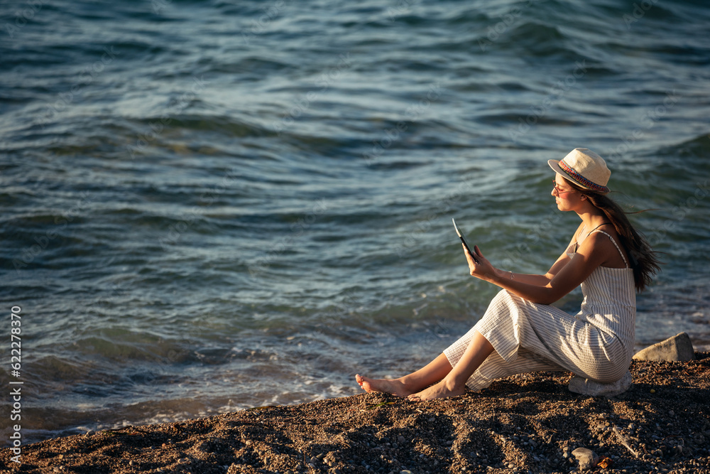 Teenage girl using a digital tablet to take pictures on the beach