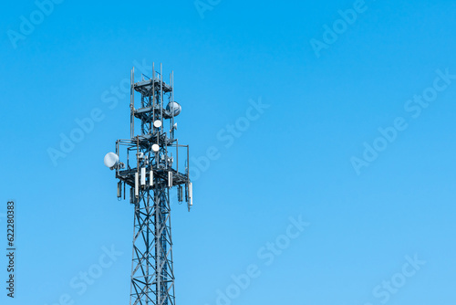 Broadcast tower 5G with satellite dishes against the clear blue sky.