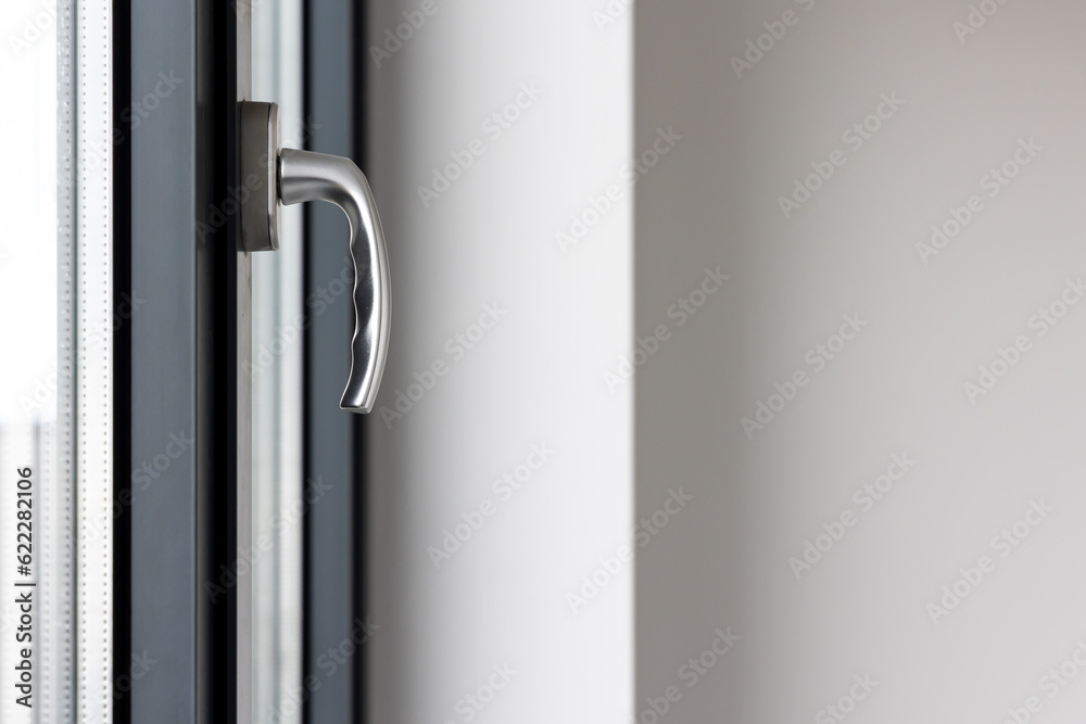 Tilt and turn window handle in a large window in a public building. The window is made of plastic, visible silicone seals.