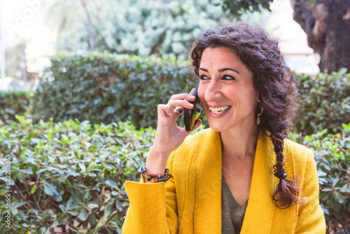 Smiling woman talking on mobile phone in a natural environment